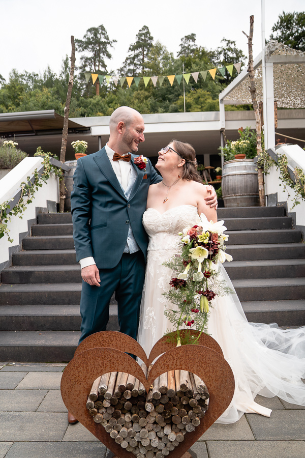 Brautpaar steht auf den Treppen der Eventlocation Schmellbachtal Leinfelden-Echterdingen und schaut sich lächelnd an