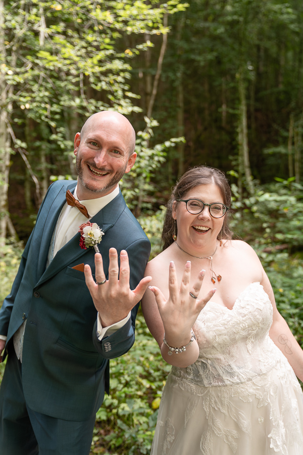 Braut und Bräutigam zeigen ihre Eheringe enthusiastisch