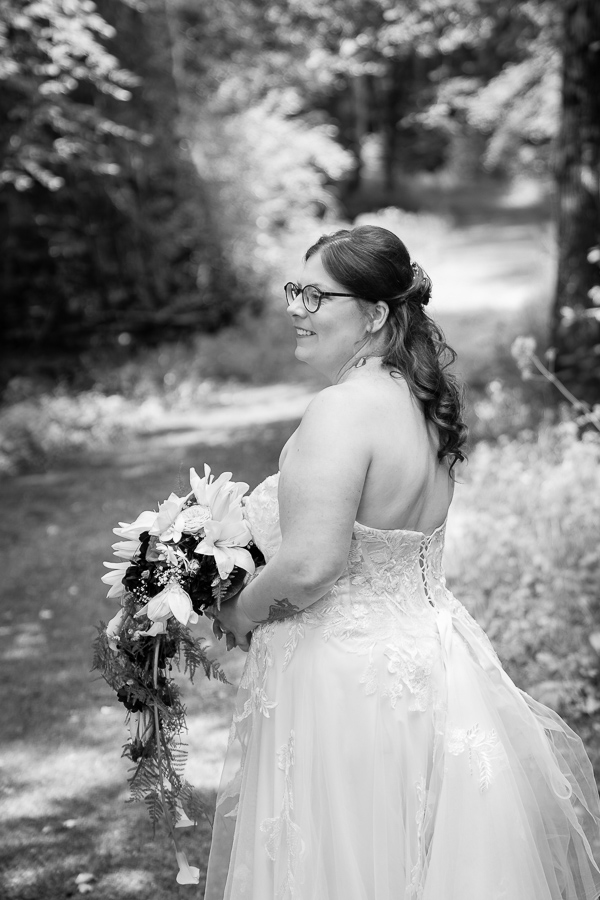 Braut steht mit Brautstrauß im Wald: Hochzeit Schmellbachtal