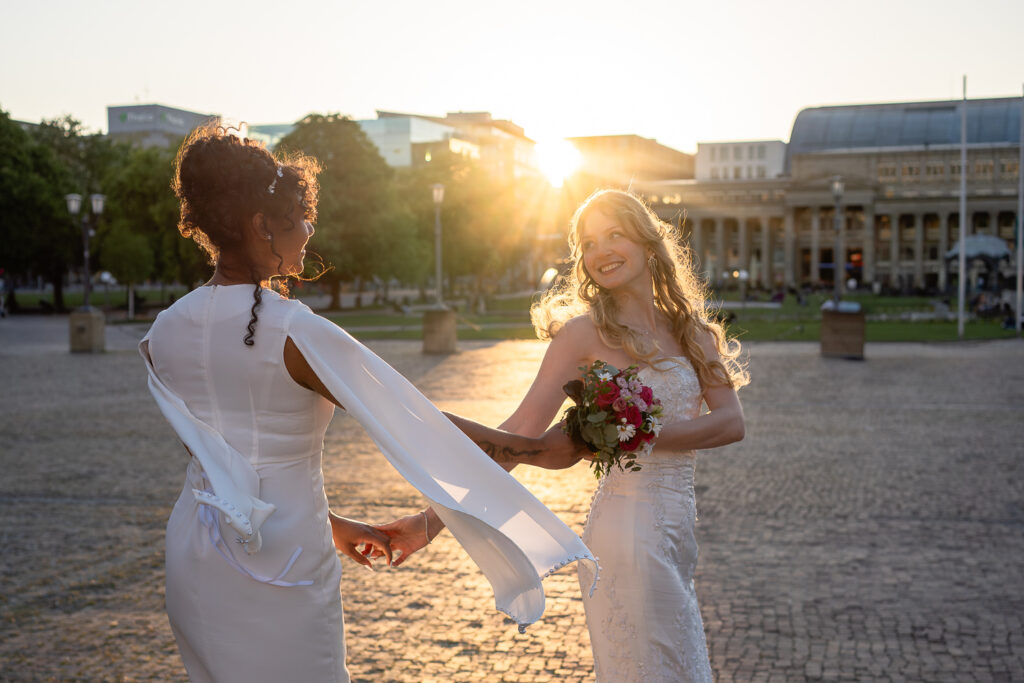 Zwei Bräute tanzen auf dem Stuttgarter Schlossplatz zur goldenen Stunde