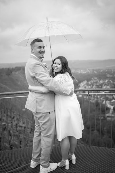 Hochzeitspaar auf Aussichtsplattform unter durchsichtigem Regenschirm
