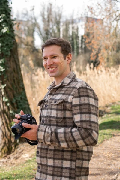 Fotograf in Karohemd steht in der Natur