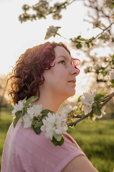 Frau mit roten lockigen Haaren ist von Blütenbaum umgeben - Portrait Fotograf Stuttgart