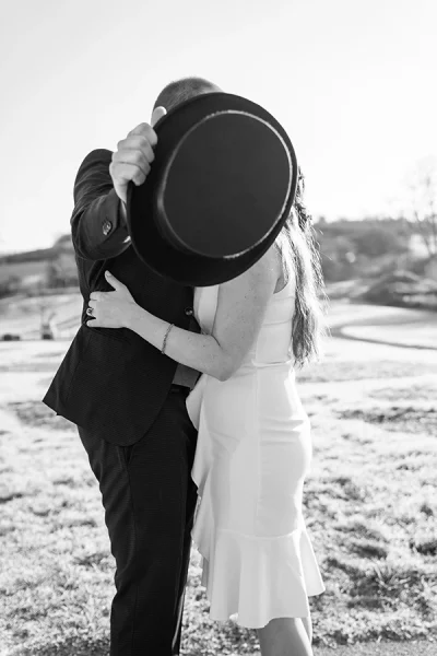 Brautpaar küsst sich und verdeckt den Kuss mit Zylinder