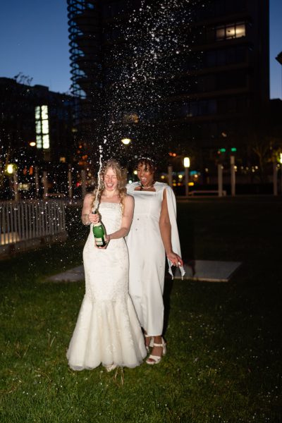 Zwei Bräute öffnen Nachts draußen in Stuttgart eine Flasche Sekt, der schäumt